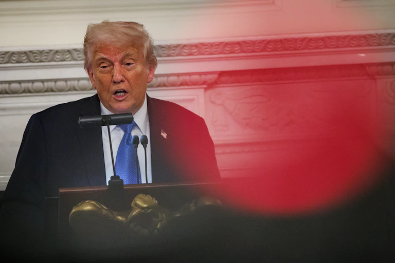 Trump speaking at a podium inside the white house