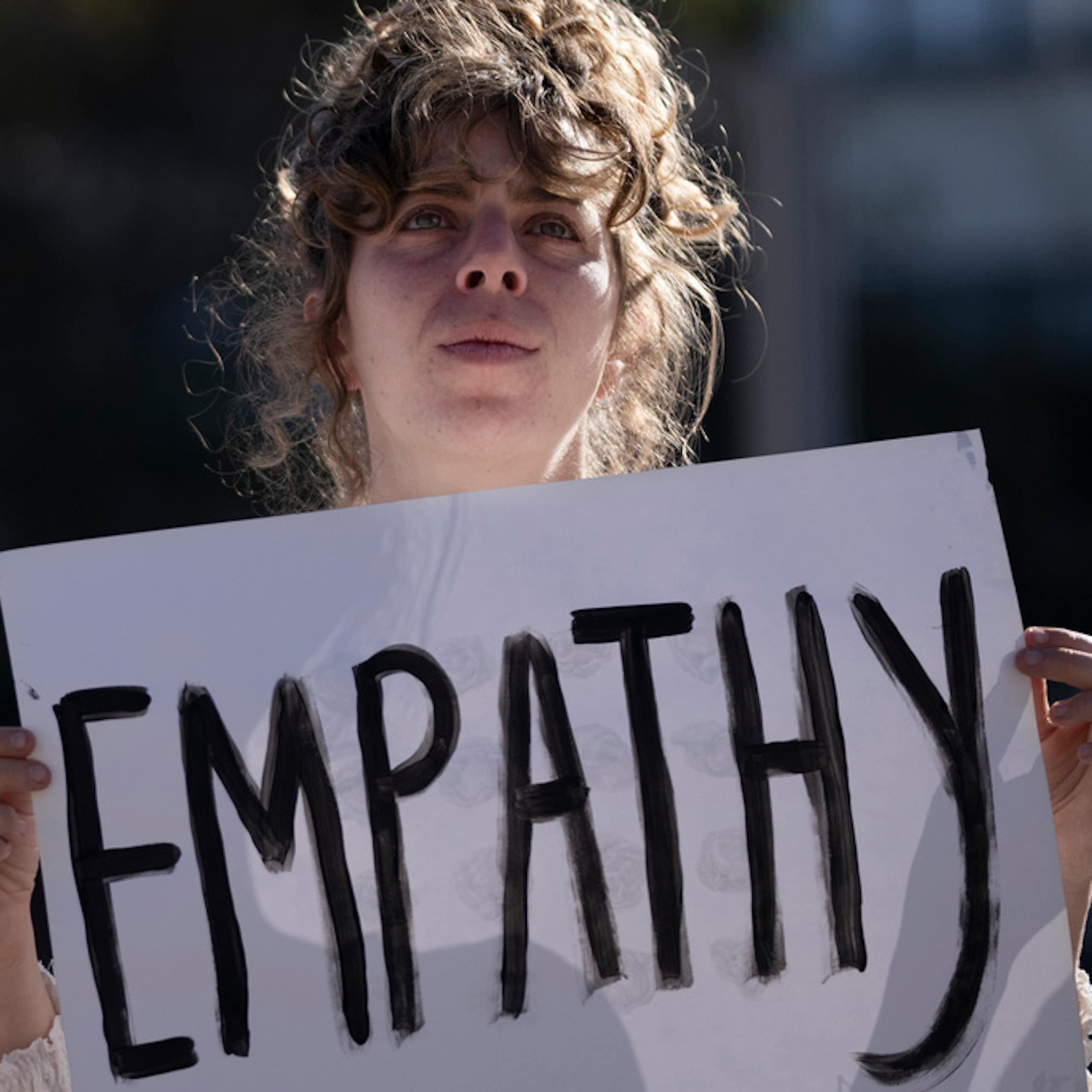 A young woman holds a placard, which says, 'Empathy.'
