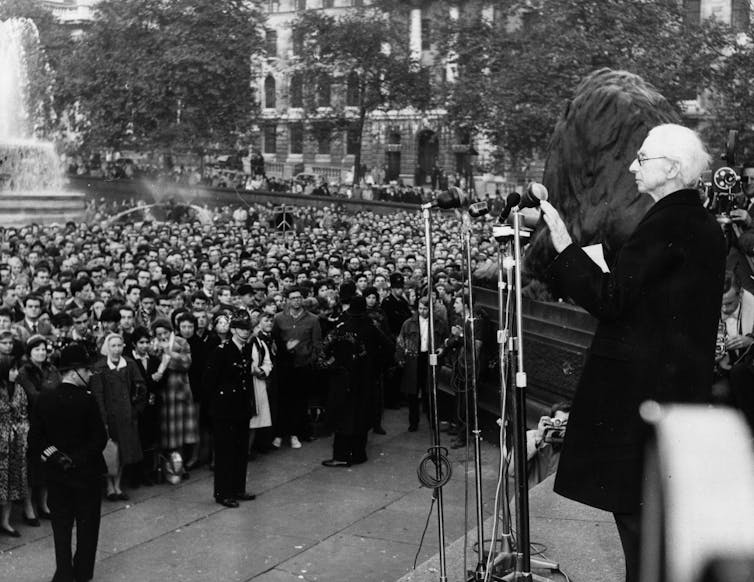 A man stands at a microphone before a crowd.