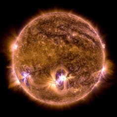 A close up of a bright star, which looks like a sphere with some flashes on its surface, against a dark background.