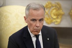 Un hombre con un cabello gris corto se ve doloroso sentado en una silla con cambio de oro.