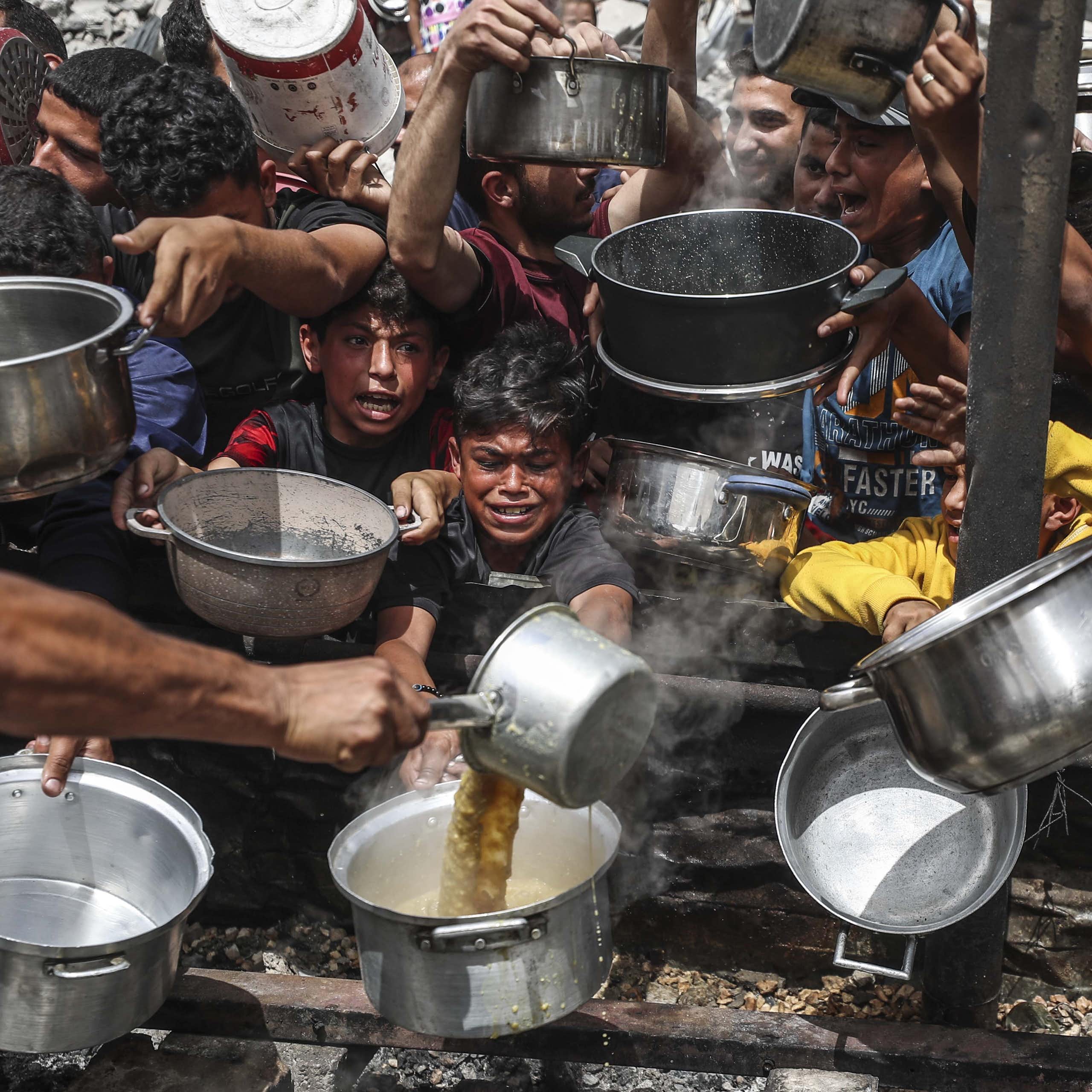 A child's face is seen between various people holding pans.
