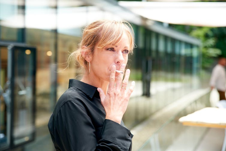 Middle-aged woman smoking cigarette outside building
