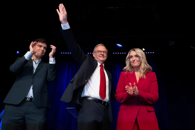 A man in a suit raises his arm in the air.