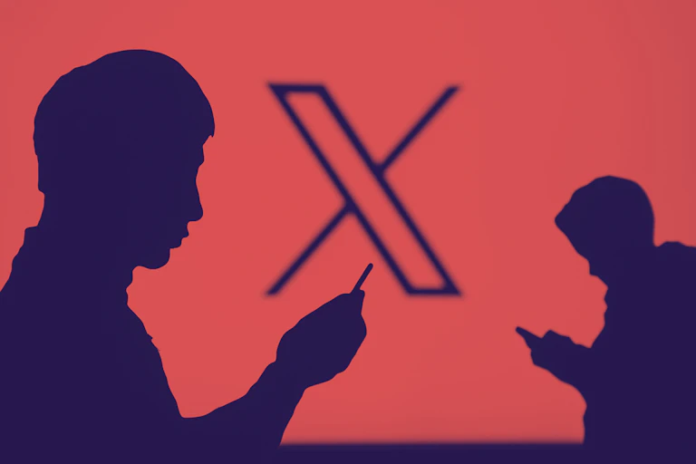 Two silhouette figures using their phones in front of a large X on a screen.