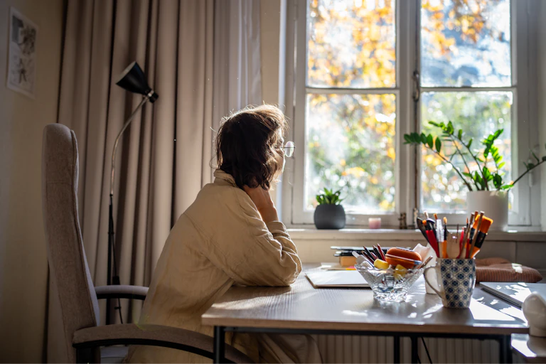 Woman at desk looking out the window.