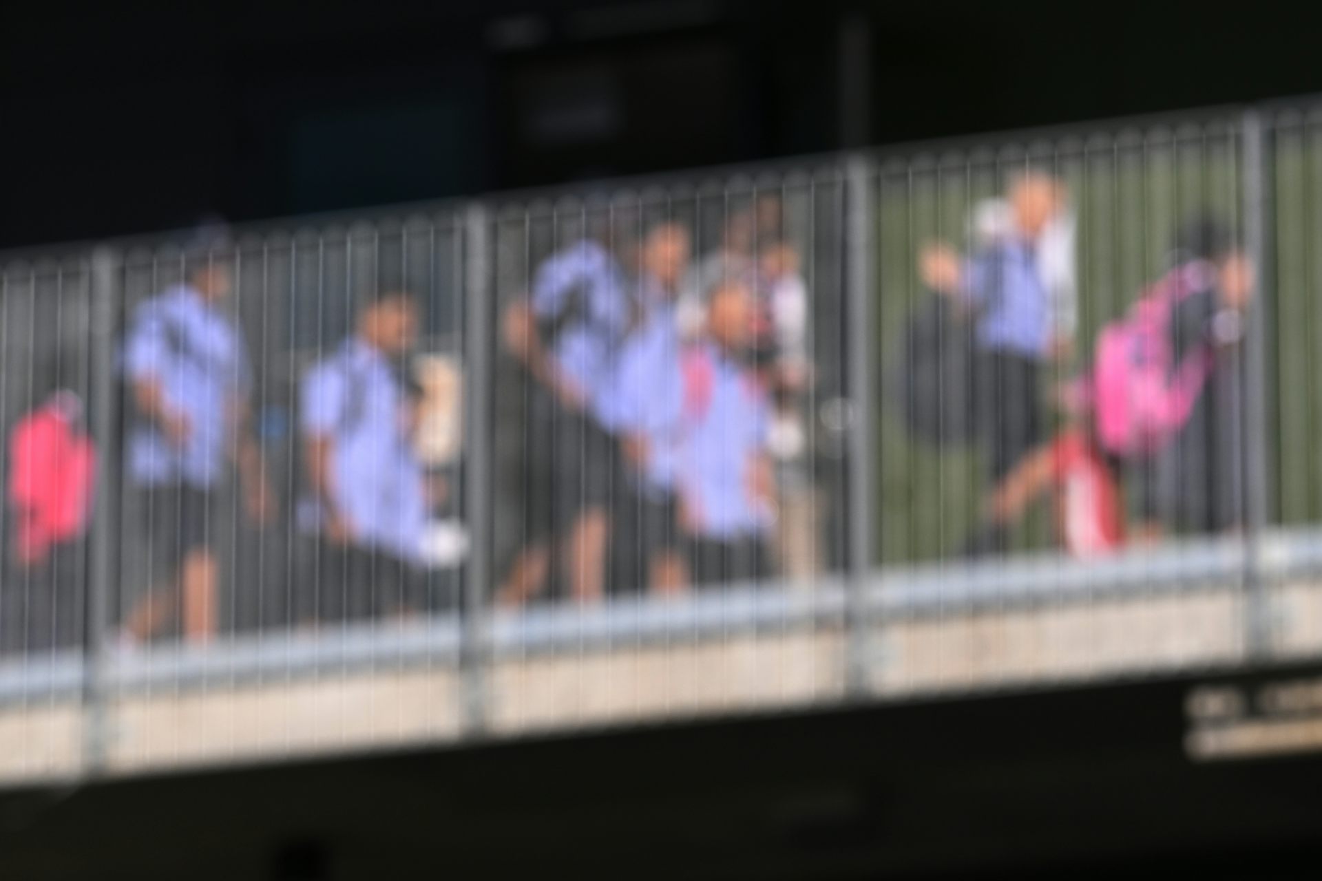 A blurred image of school students in uniform crossing a walkway.