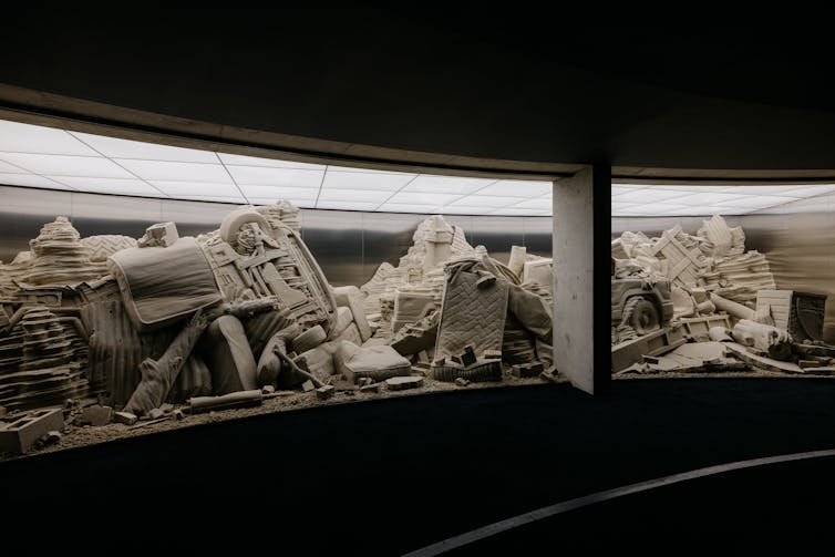 The sculpture behind a curved glass wall.