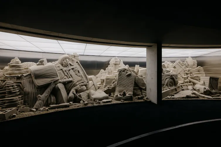 The sculpture behind a curved glass wall.