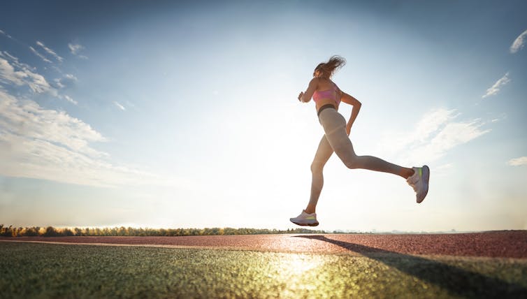 A woman goes for a run at sunset.