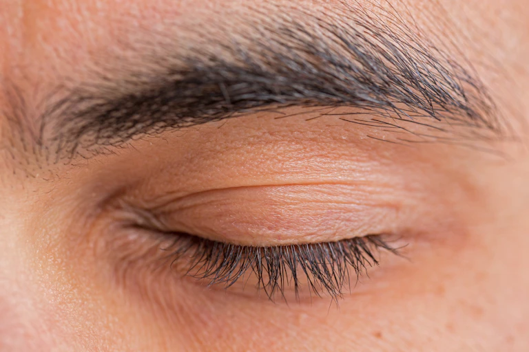 A man closed eyelid, showing his eyelashes.