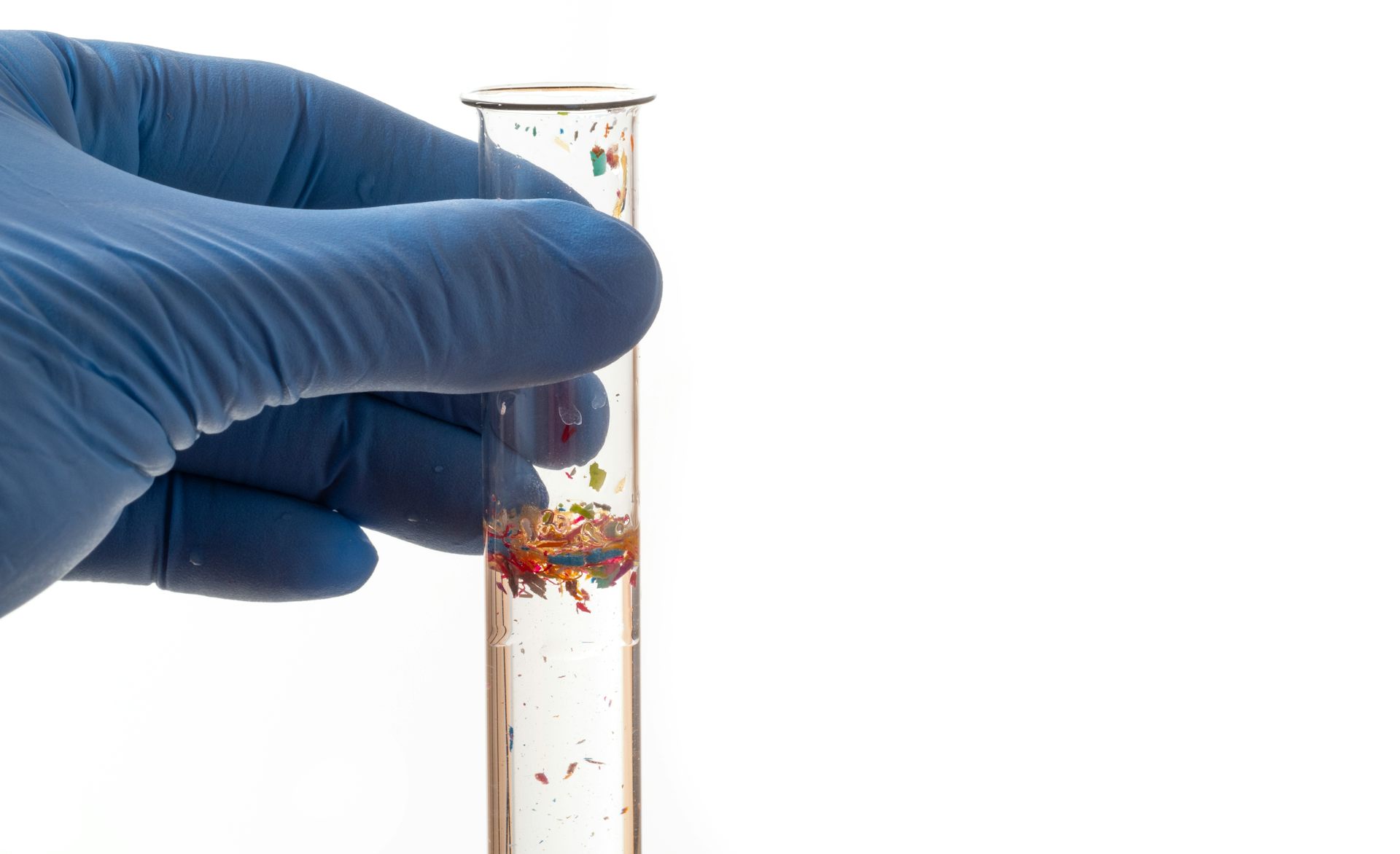 une main gantée tient un tube à essai