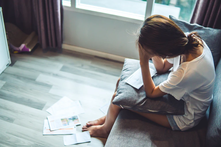 Young woman sitting on a sofa worried about bills