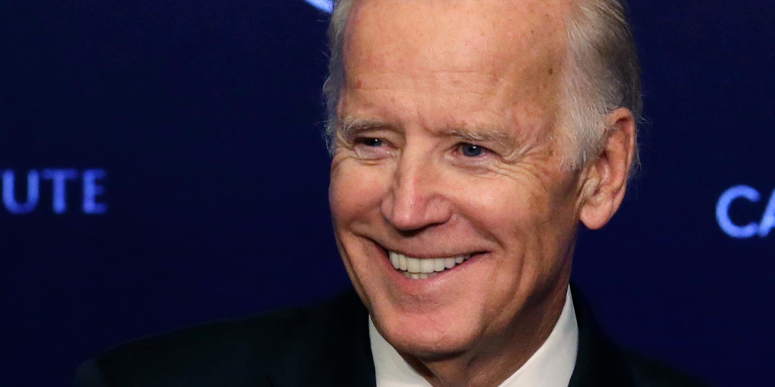 Joe Biden smiling in front of a backdrop reading 'CANCER MOONSHOT'