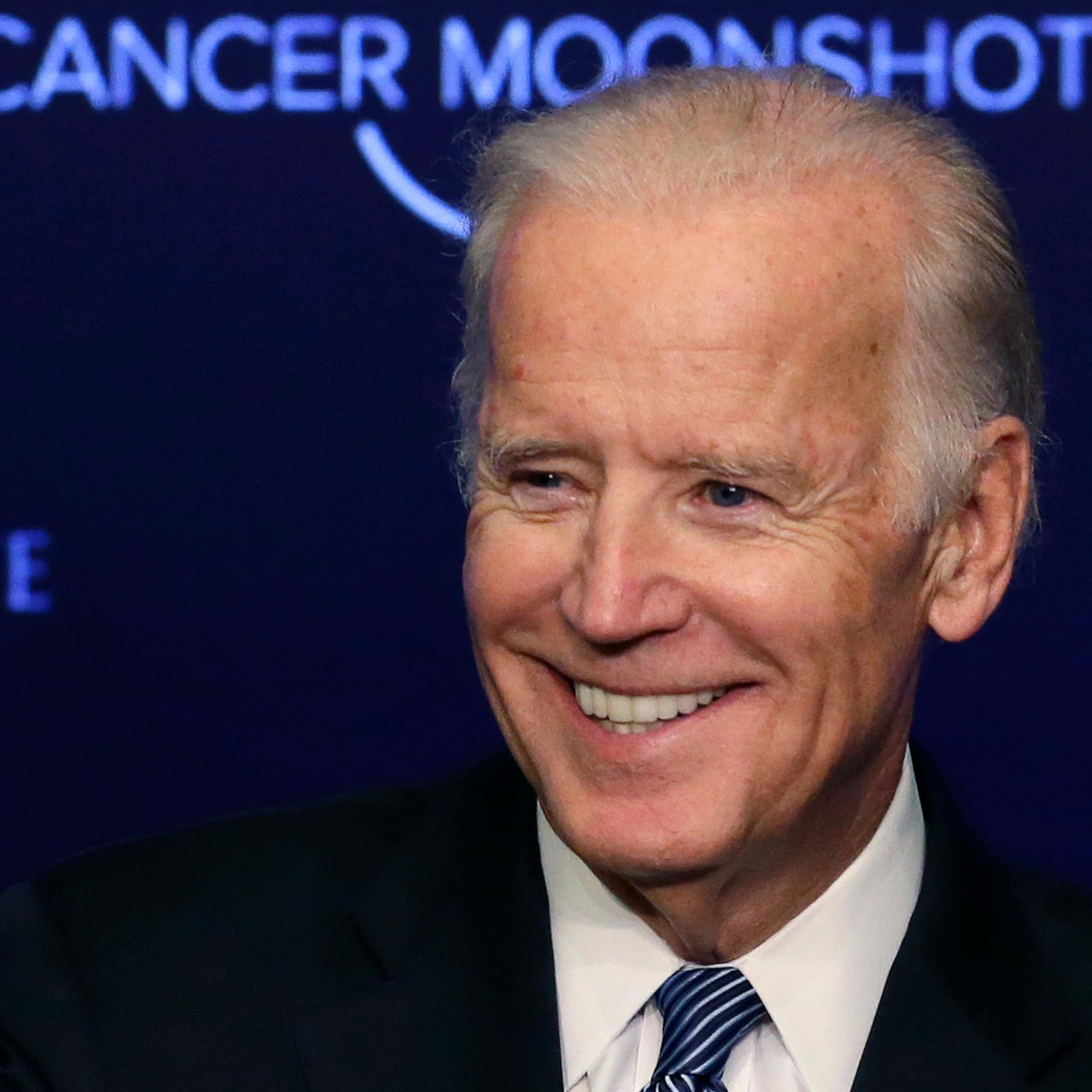 Joe Biden smiling in front of a backdrop reading 'CANCER MOONSHOT'