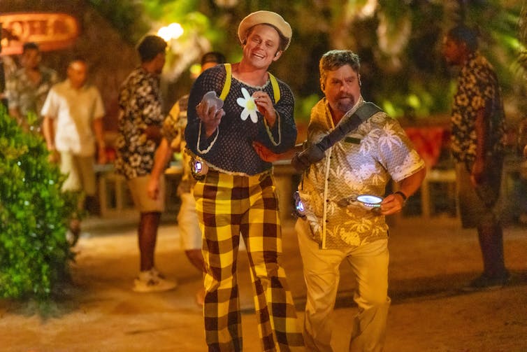 Two men garishly in flamboyantly patterned clothes and hats.