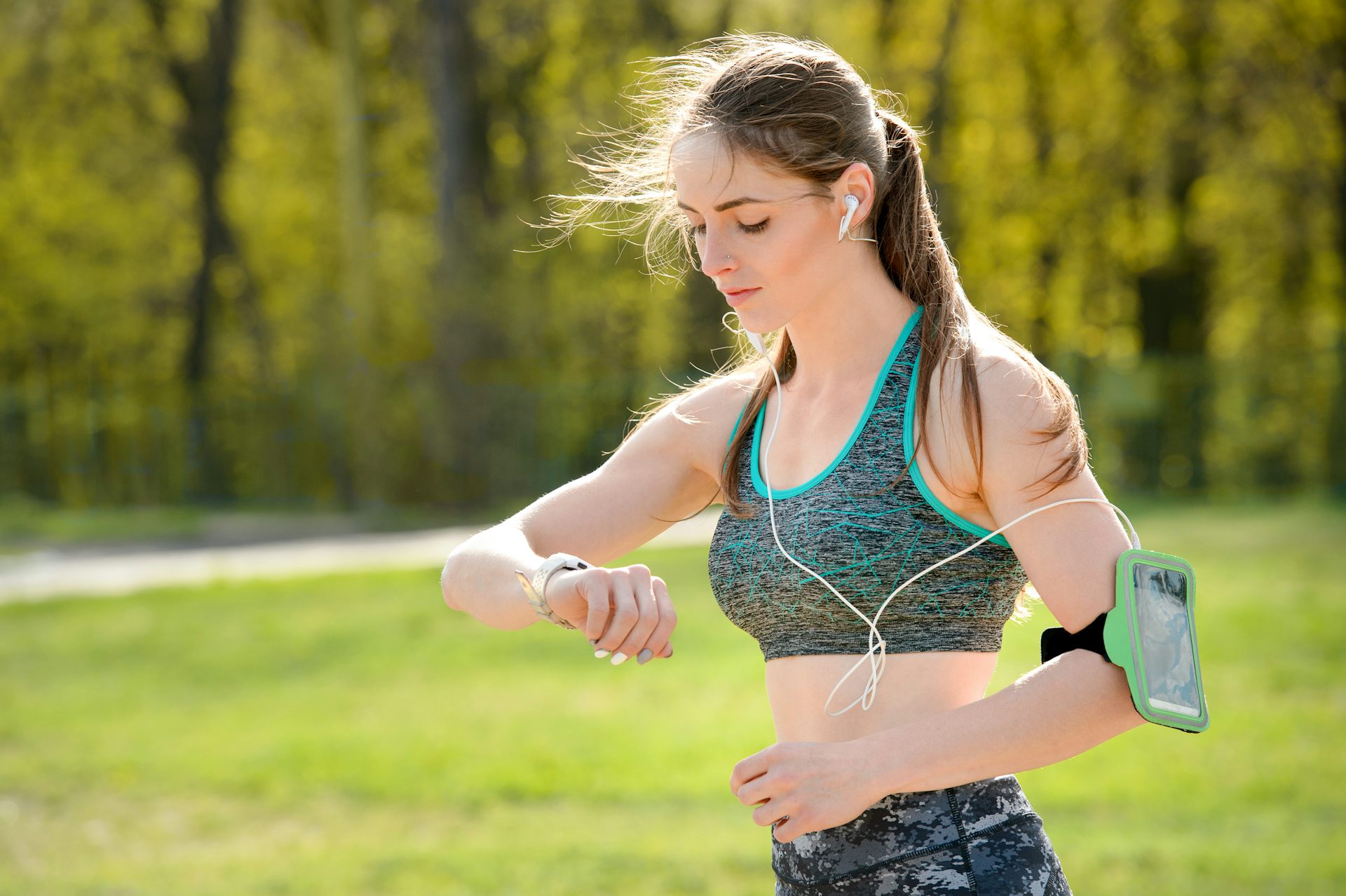 Une jeune femme, en train de faire du sport, consulte sa montre connectée.