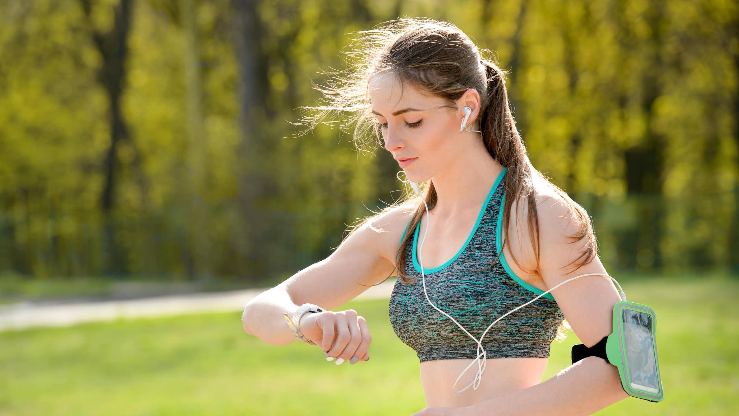 Une jeune femme, en train de faire du sport, consulte sa montre connectée.