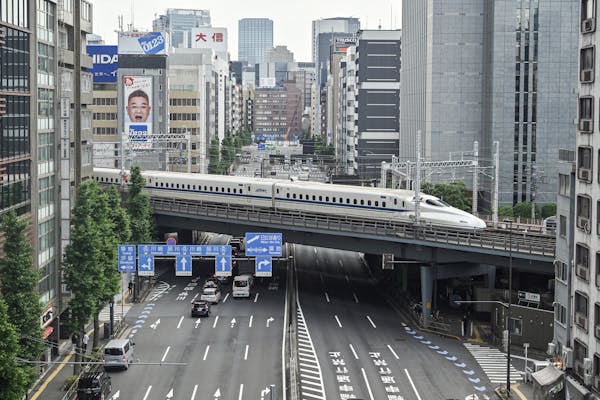High-speed bullet train crosses bridge between skyscrapers
