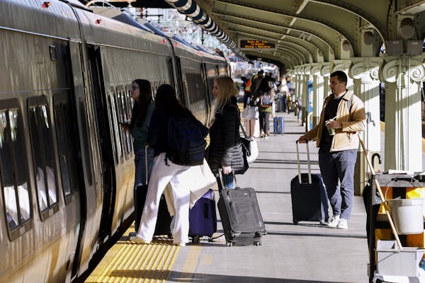 Passengers stand on platform waiting to board a train