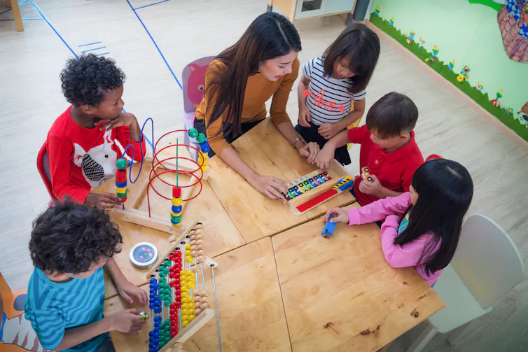 Children and an educator at a table.