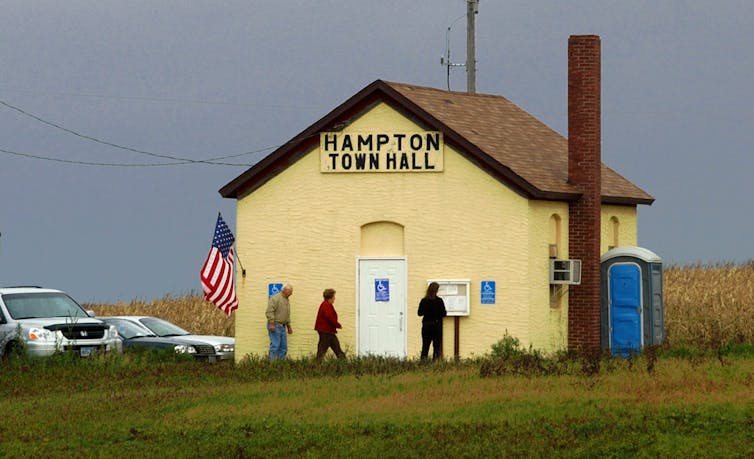 A small, yellow town hall with a chimney.