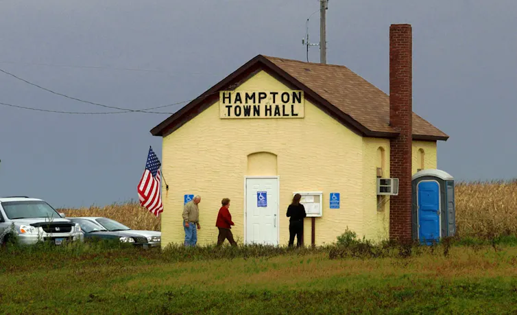 A small, yellow town hall with a chimney.