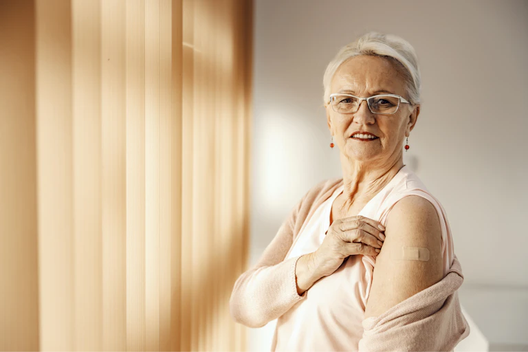 Older adult white woman showing off her vaccine injection.