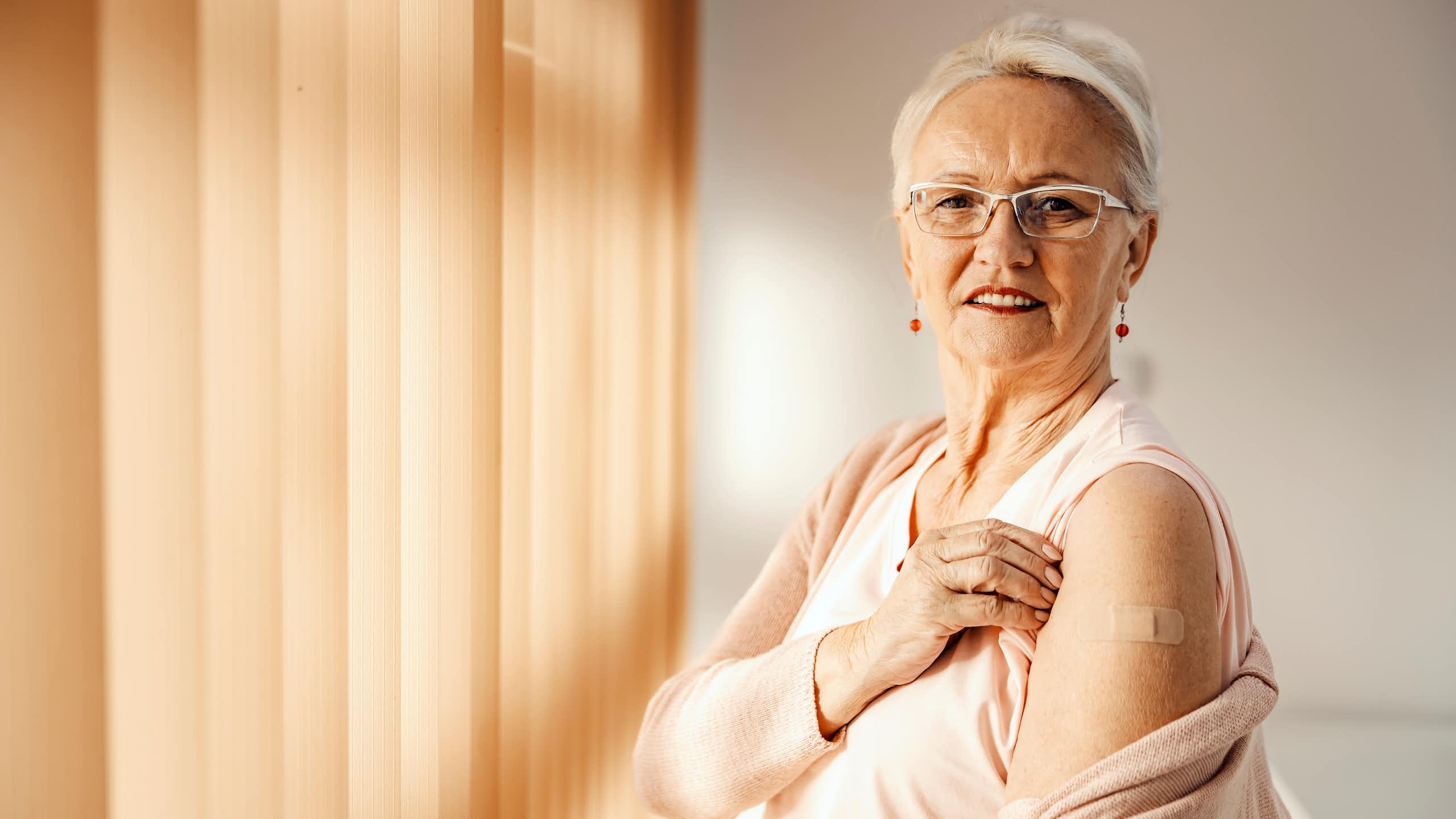 Older adult white woman showing off her vaccine injection.