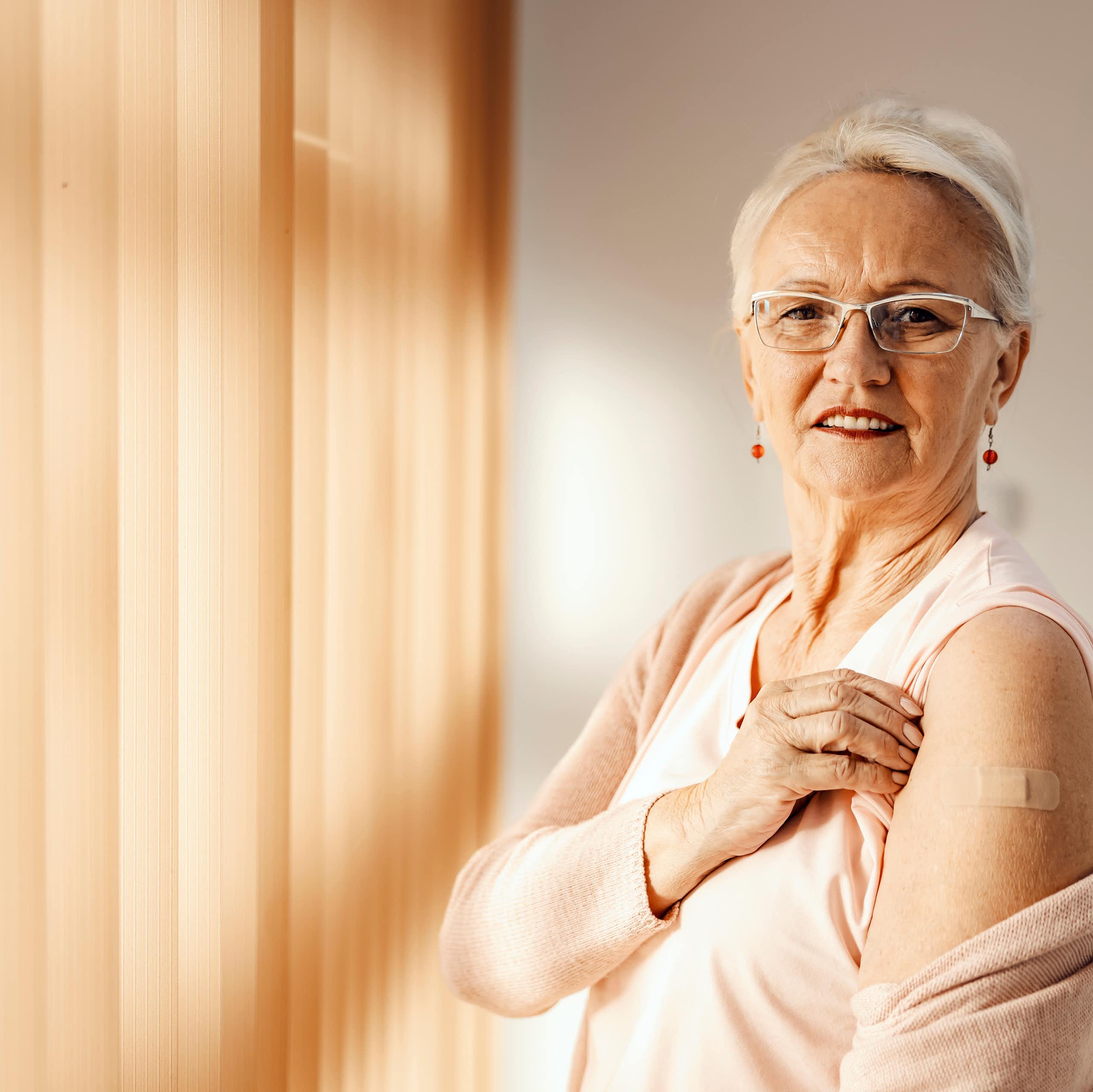 Older adult white woman showing off her vaccine injection.