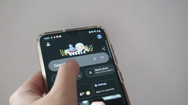 a hand holding a smartphone showing Google search