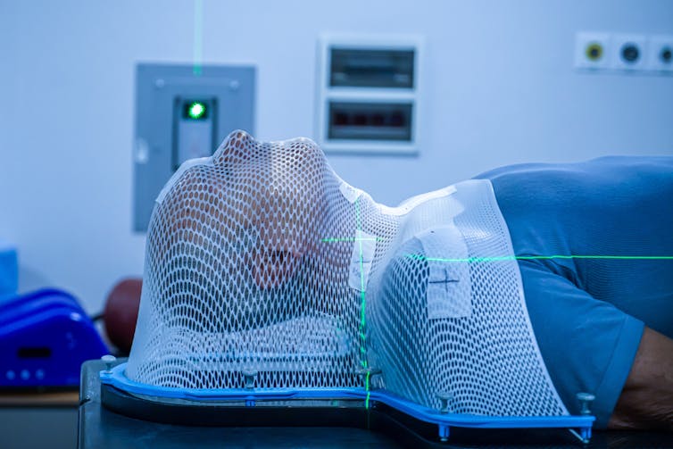 a person lying down with their head and shoulders covered by a white netting