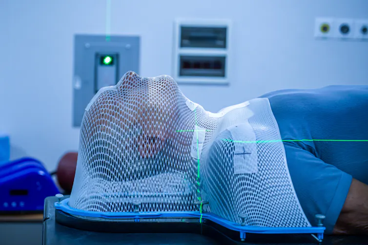 a person lying down with their head and shoulders covered by a white netting