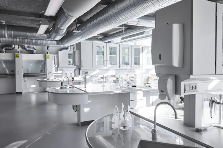 an empty lab space with multiple sinks, counters and cabinets