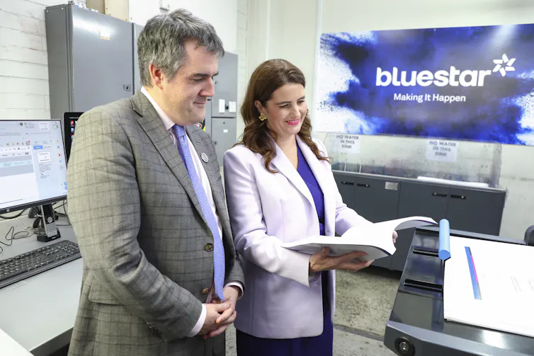 Nicola Willis and Chris Bishop look down at a copy of the New Zealand 2025 Budget.