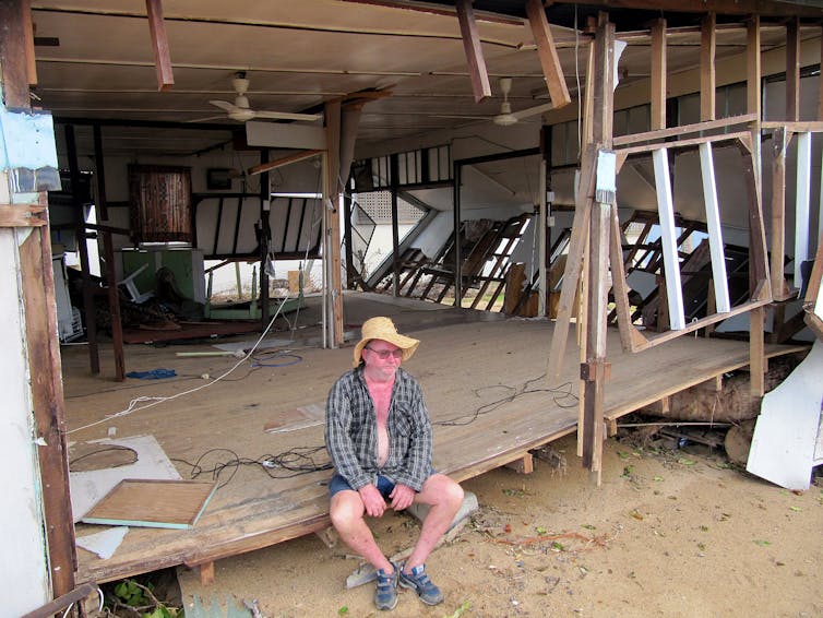 Man sitting on edge of ruined house after Cyclone Yasi, Queensland 2011