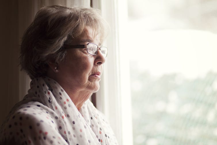 A senior woman looking out a window.