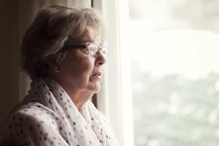 A senior woman looking out a window.