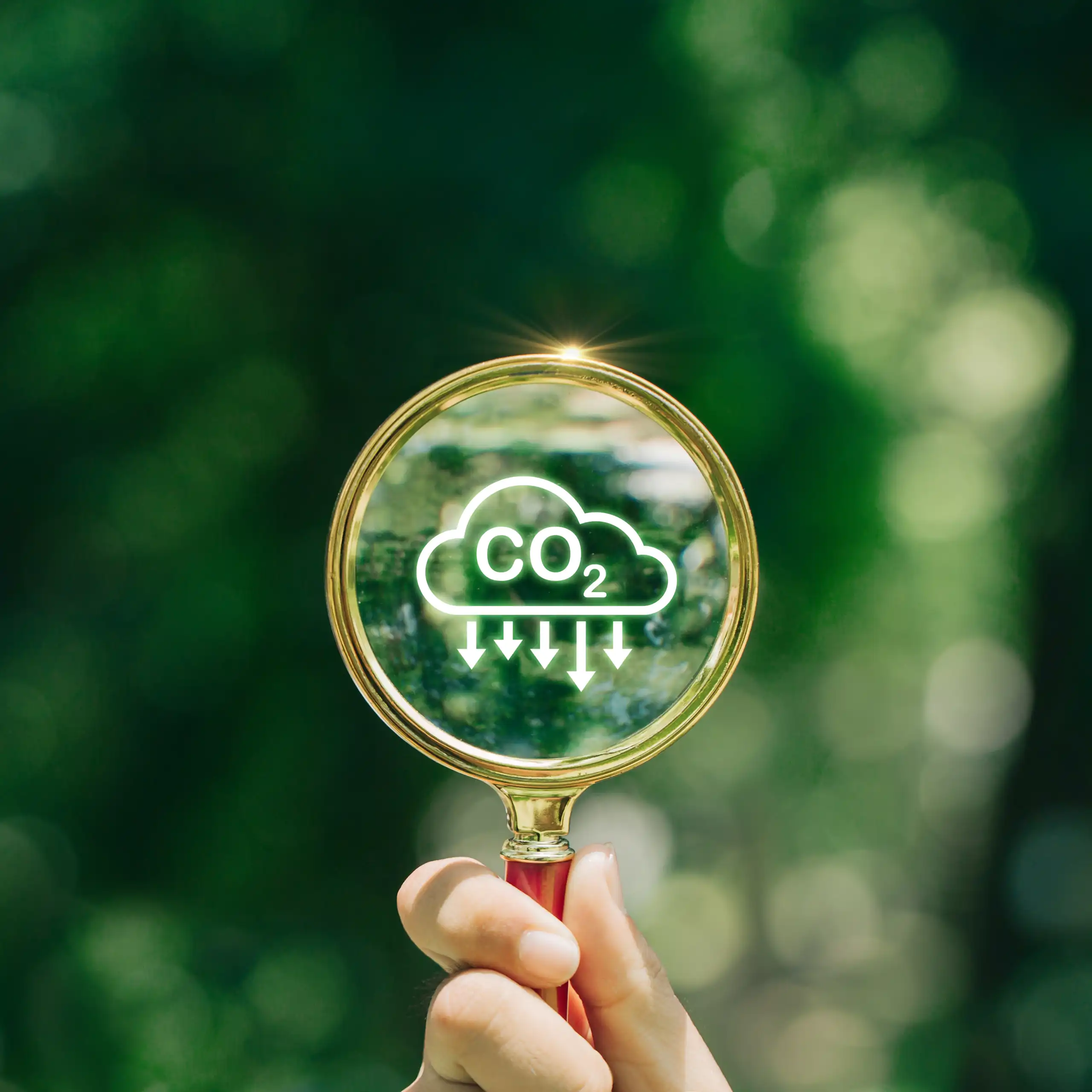 Una mano sujetando una lupa con el símbolo del CO2 dentro de una nube