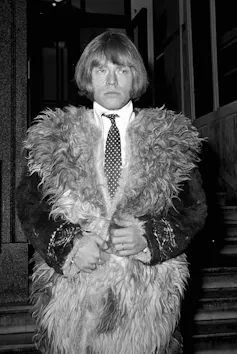 Brian Jones wears an Afghan coat over a shirt and tie