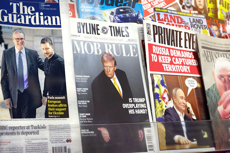 A newsstand with coverage of Donald Trump, Vladimir Putin and Volodymr Zelensky in various newspapers and magazines.