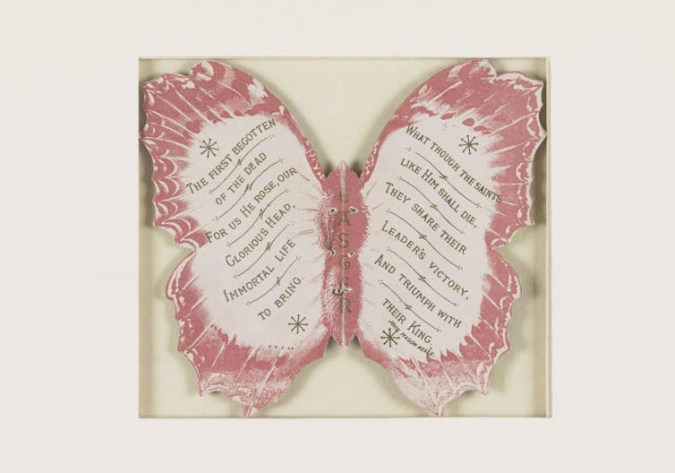 A red-and-white cardboard butterfly with text written on the wings.