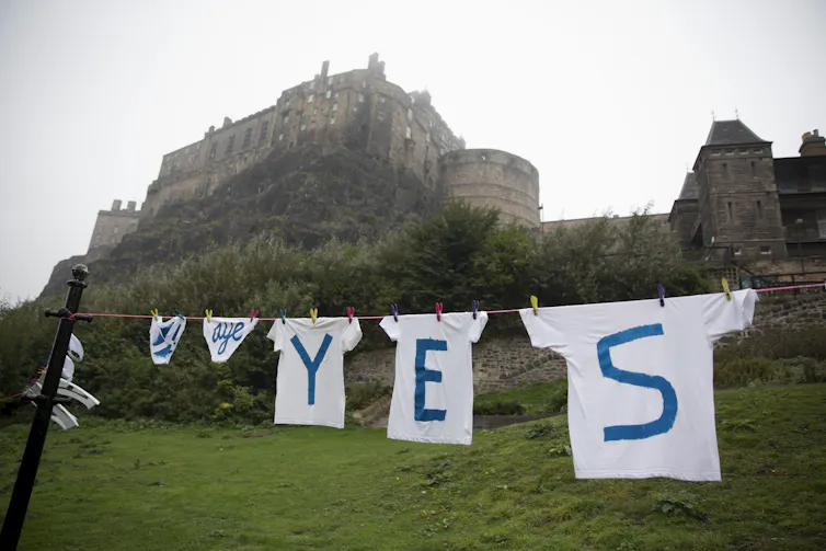 A clothesline with shirts that spell out Yes and a looming castle behind it.