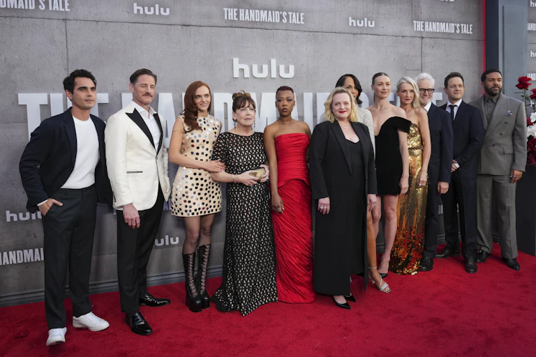 People in fancy clothes on a red carpet.