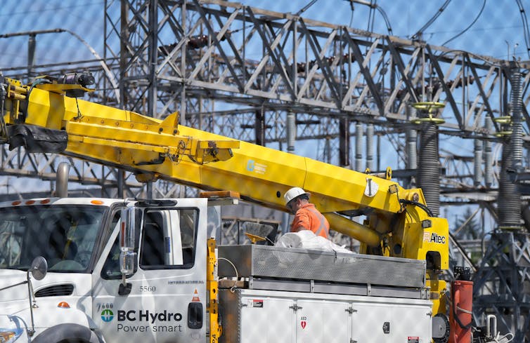 Vehículos municipales con el logotipo de BC Hydro sobre él. El hombre con un sombrero duro se encuentra boca arriba