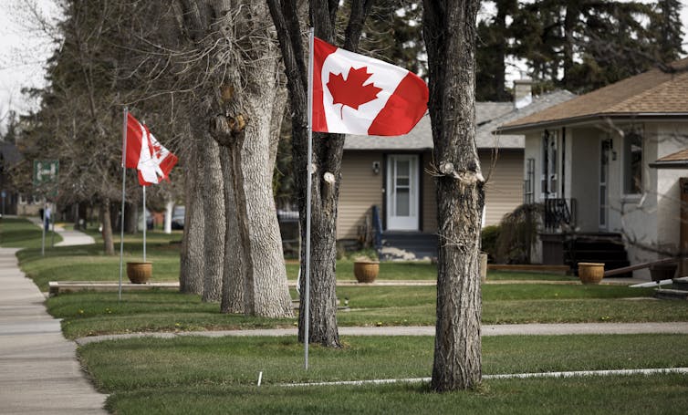 Banderas canadienses frente a las casas en una calle residencial.