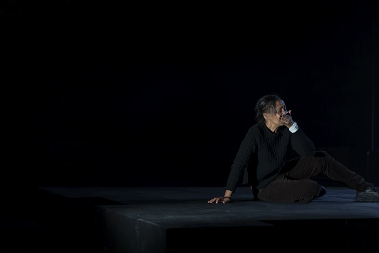 Paula Arundell sits on a black stage.