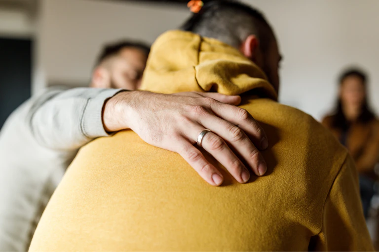 A person being hugged during a therapy session