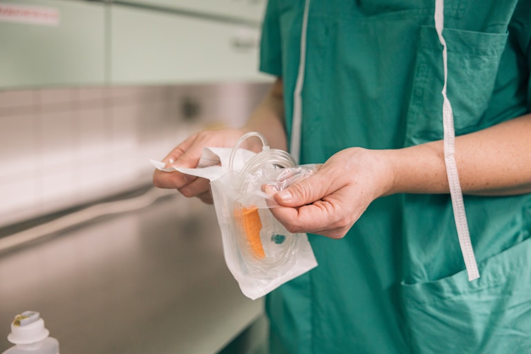 Medical staff member setting up an IV catheter.