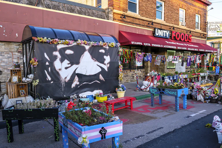 A mural of a man is seen next to a grocery store.